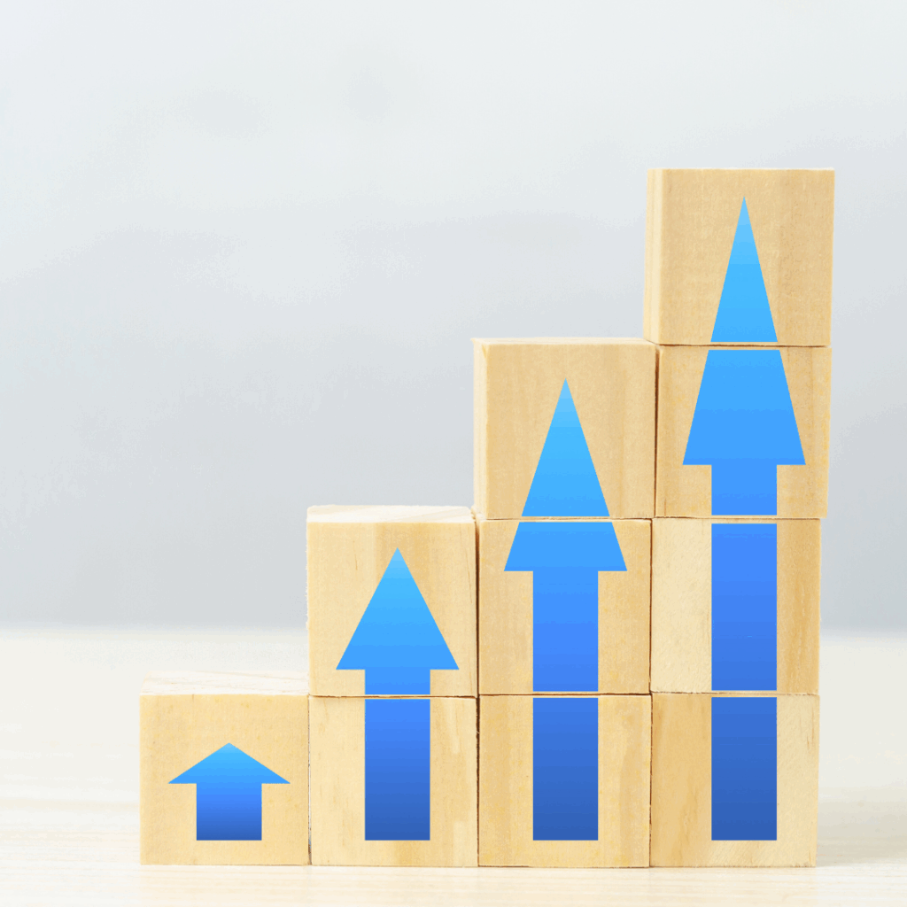 Five stacks of wooden blocks increase in height from left to right. Each stack has a blue arrow pointing upward, symbolizing growth or progress, with the arrows becoming larger as the stacks get taller.